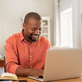 Man smiles while working on a laptop