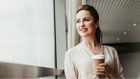 A person looks out the window while holding a coffee cup.