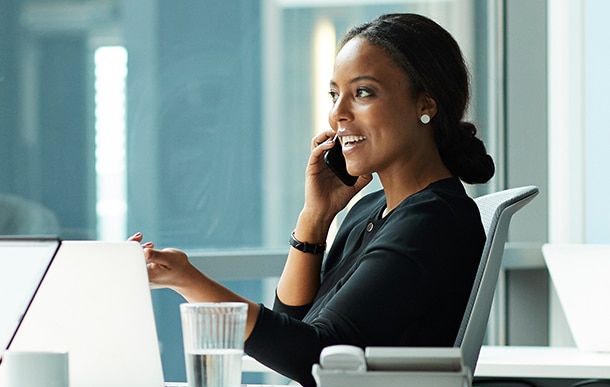 An advisor smiles while talking on the phone at their desk.