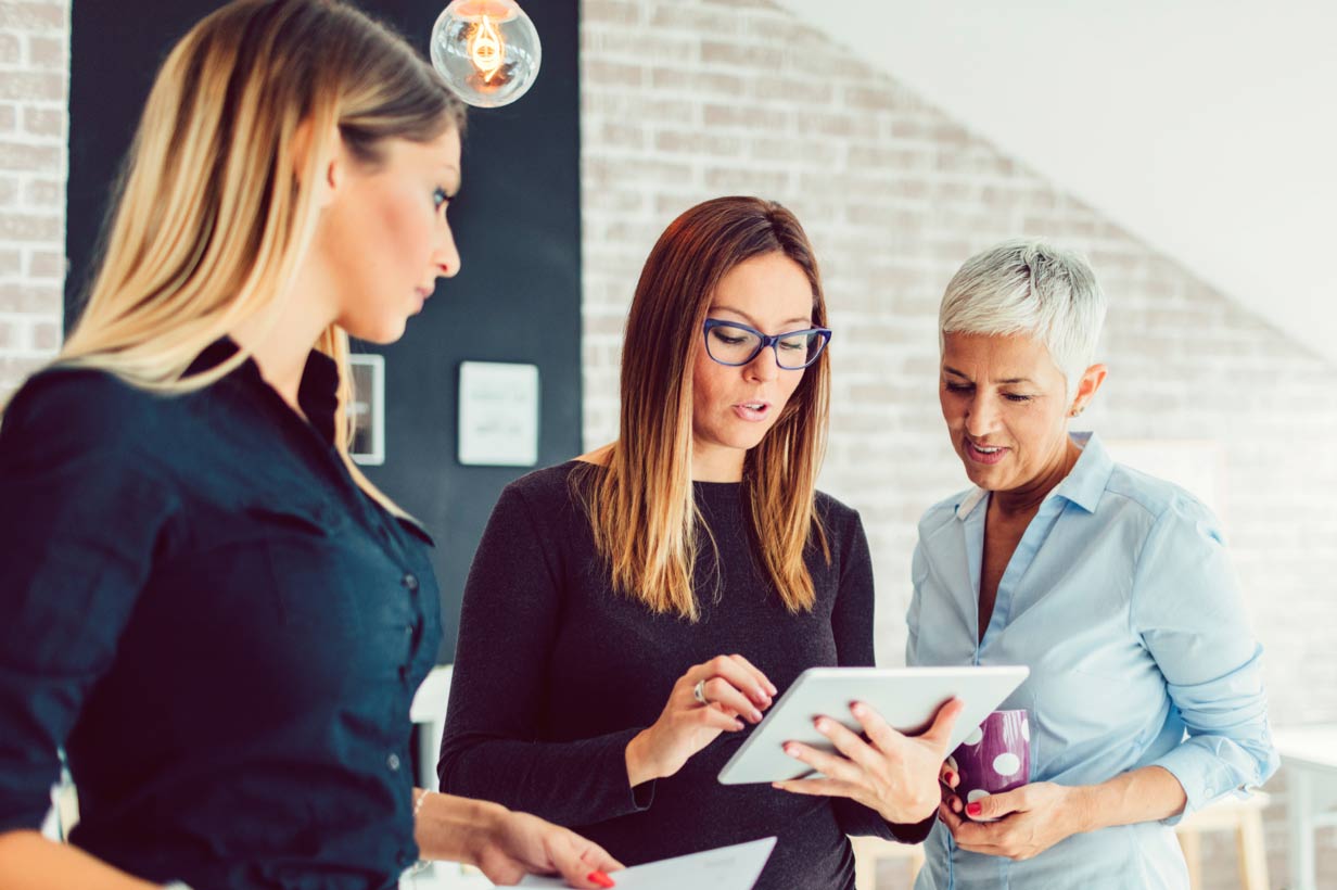 Three investment advisors in front of a computer review the results of the annual RIA Benchmarking Study.