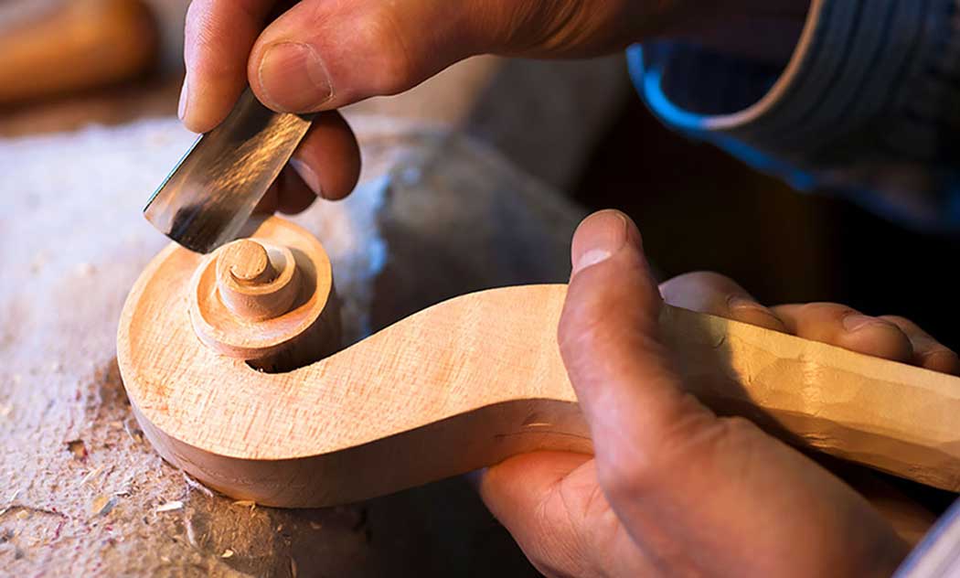 A close-up of hands carving wood artistically