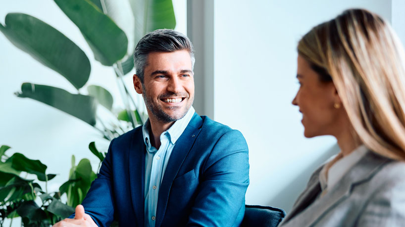 Two smiling professionals work together at a laptop