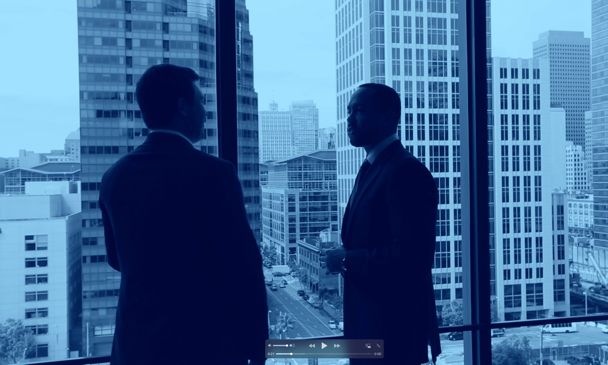 Two men in an office standing near a window