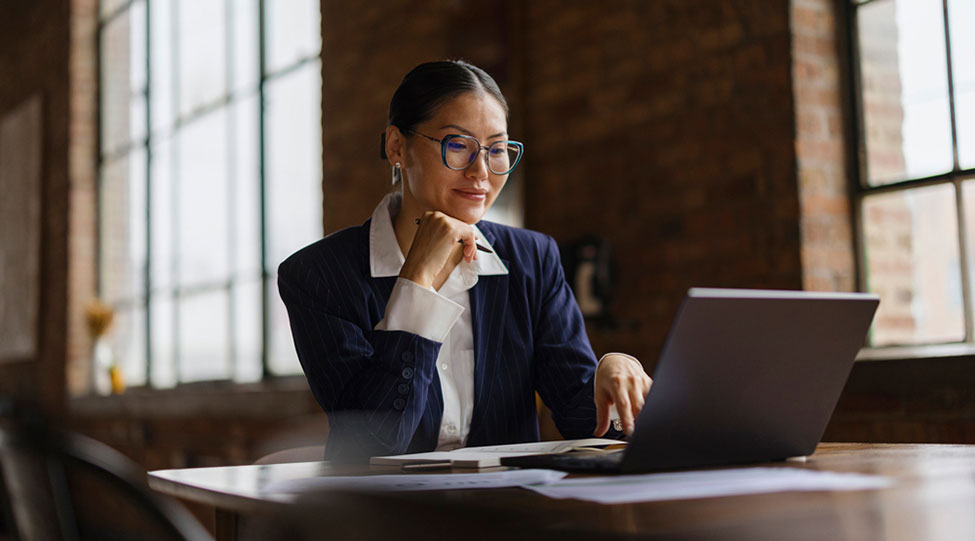 A professional smiles while using a laptop